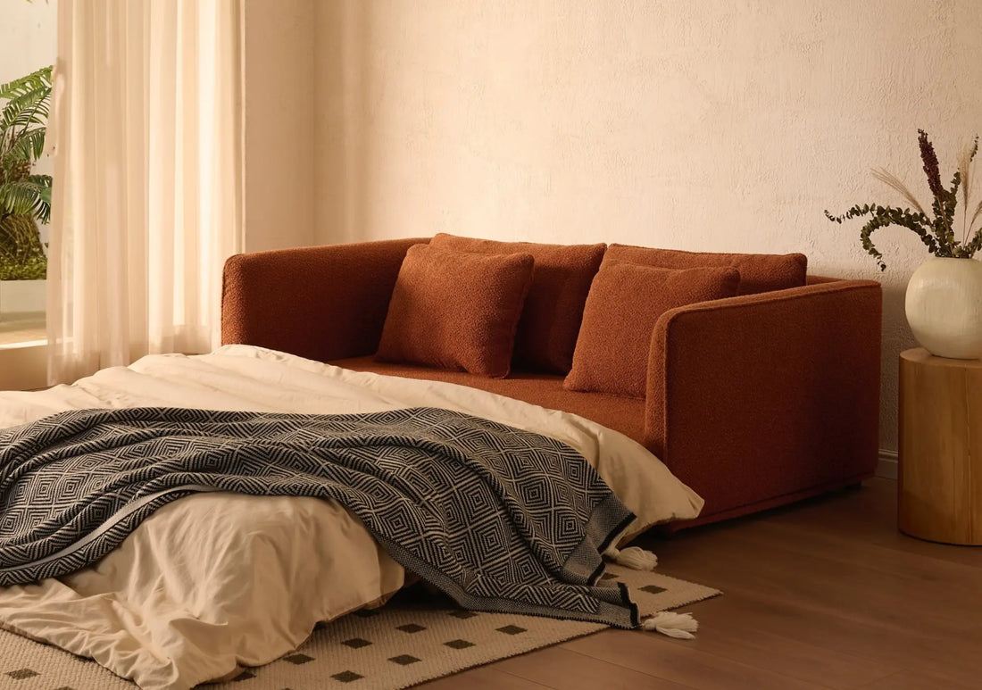 Anti-scratch sofa in burnt orange upholstery positioned at the foot of a bed in a contemporary bedroom