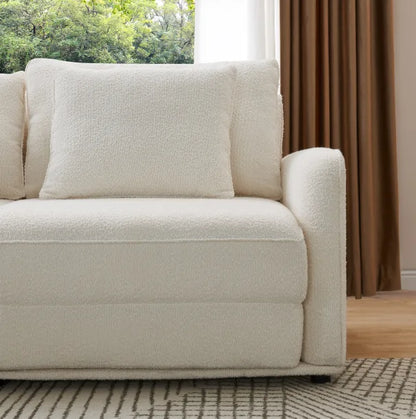 Close-up of cream boucle Sunset Sofa Bed corner with matching cushion on a patterned rug.