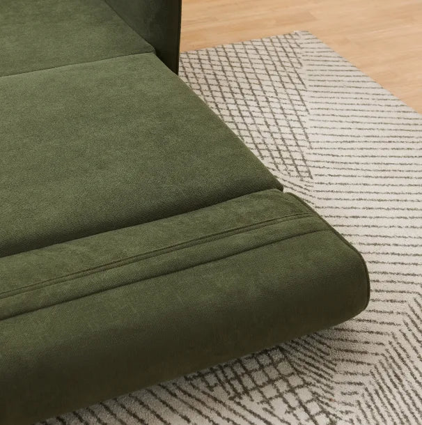Close-up of olive green upholstered sofa bed cushions showing soft fabric texture on a patterned cream rug.