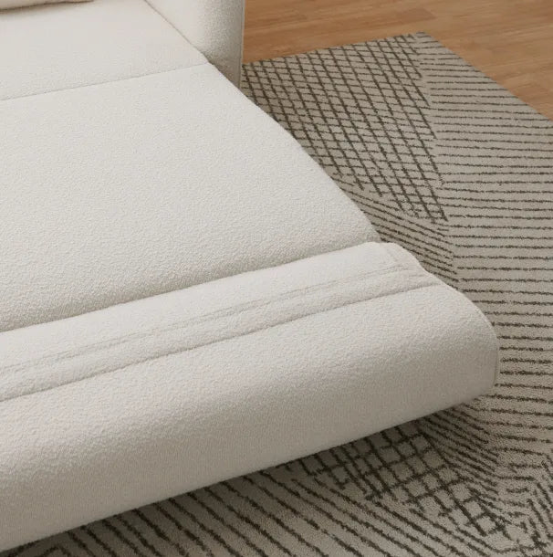 Cream bouclé Sunset Sofa Bed corner resting on a geometric patterned rug.