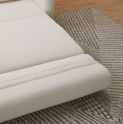 Cream bouclé Sunset Sofa Bed corner resting on a geometric patterned rug.